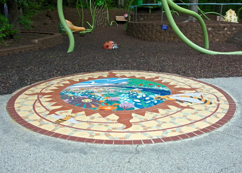 Follow the Pollen Path, a ceramic tile mural, inlaid in front of the Garden Friends playground. 