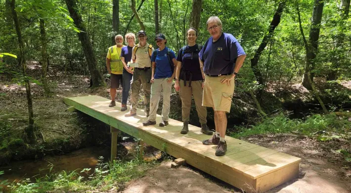 Trail building Team standing on a bridge in the woods